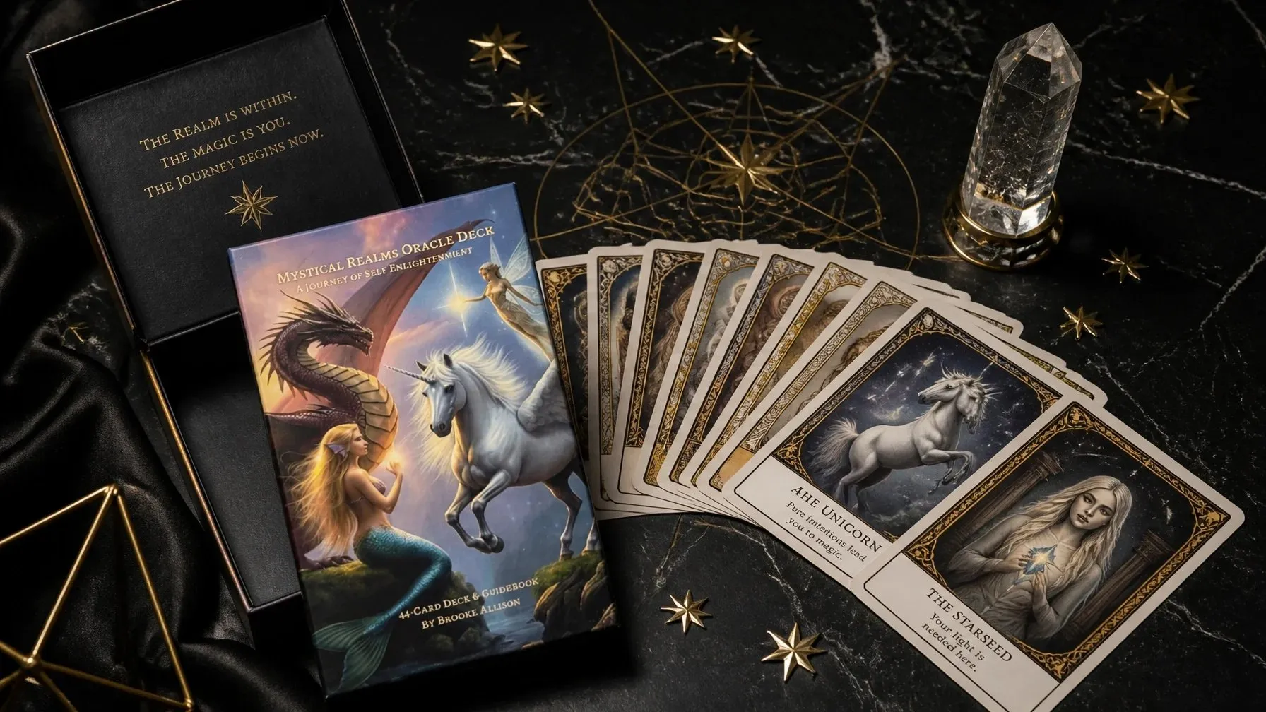 Mystical Realms Oracle Deck cards and box arranged on black marble with celestial objects